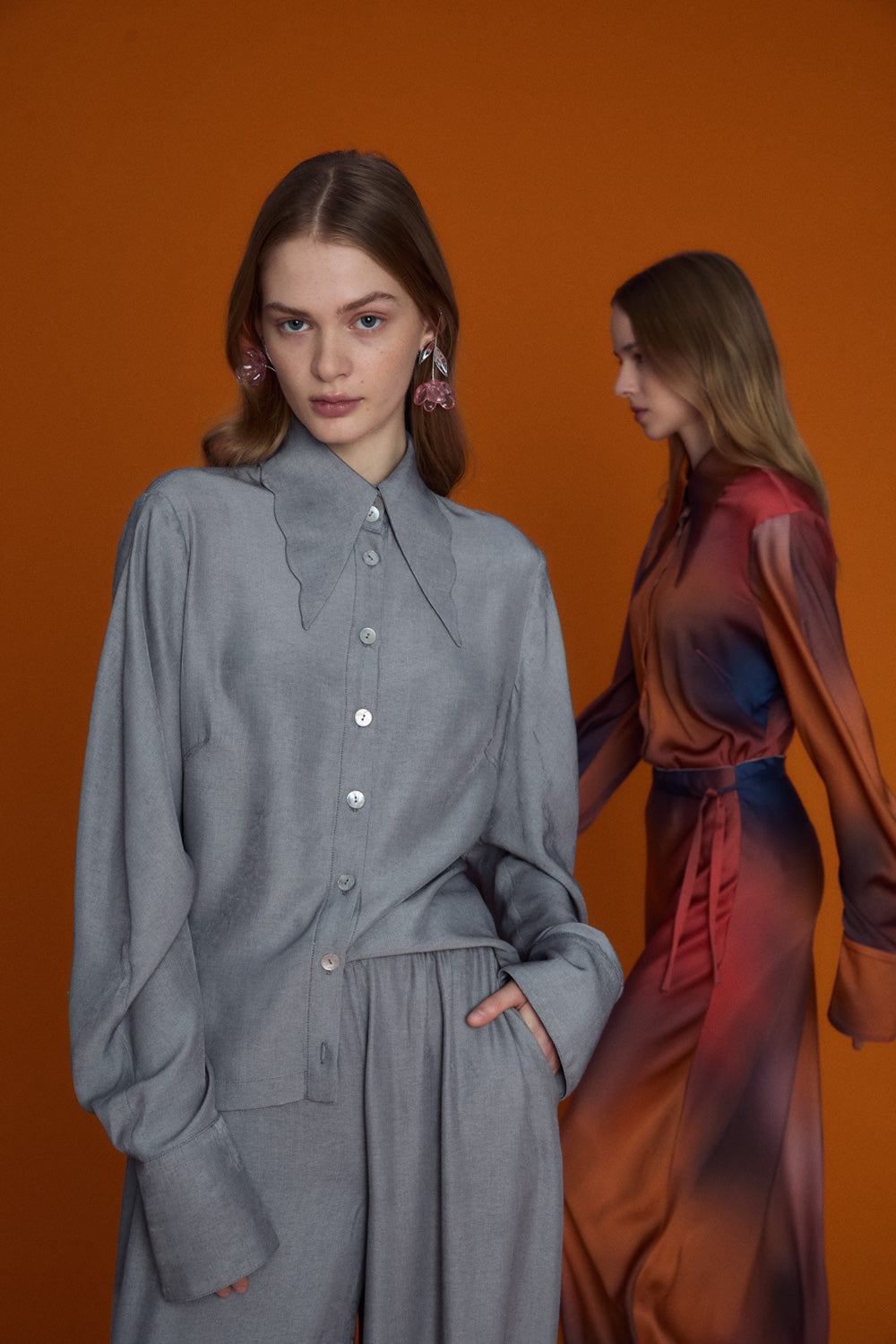 Soft grey oversized blouse with a gentle ruffled collar and relaxed silhouette, photographed against a clean neutral background
