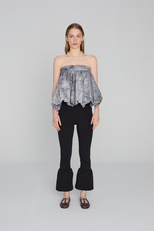 “Fitted 3/4-length leggins trousers with a wide flowing ruffle hem, in soft fabric that hugs like leggings with a comfortable waistband, styled on a clean background.”