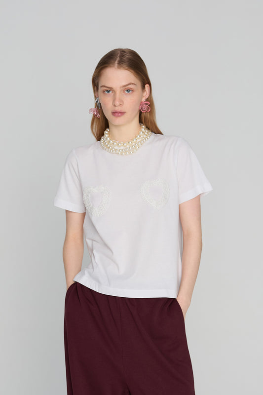 Oversized soft t-shirt with a minimalist embroidered heart motif on the chest, photographed against a clean neutral background.