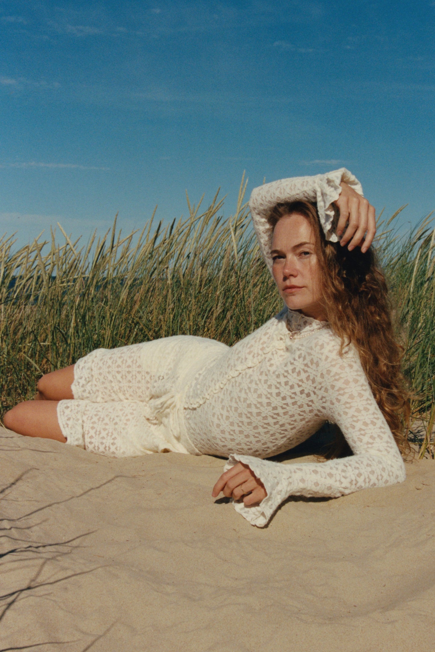 Delicate sheer lace top with a floral encaje pattern and soft draping silhouette, photographed against a clean neutral background.